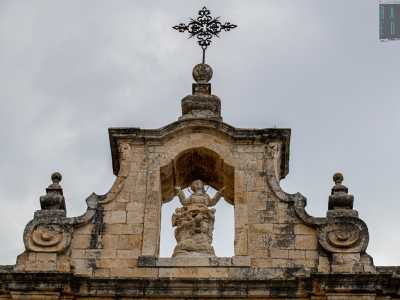 Il coronamento presenta dei pinnacoli ai lati e un fastigio �a baldacchino� che racchiude una statua della Madonna in gloria con angeli